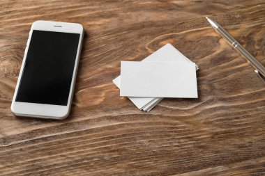 Cep telefonu ve ahşap masa üzerinde kalem ile boş kartvizit