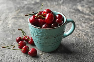 Olgun kiraz gri arka plan üzerinde fincanla