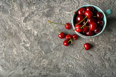 Olgun kiraz gri arka plan üzerinde fincanla