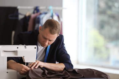 Atelier dikiş makinesi üzerinde çalışan genç terzi