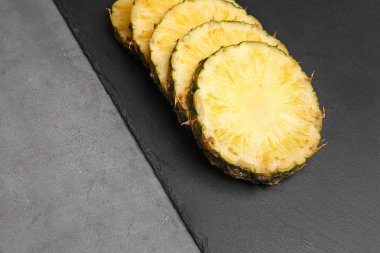 Gri arka plan üzerinde olgunlaşmış ananas dilimleri ile kayrak plaka