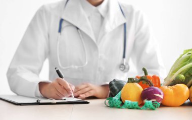 Masada Pano ve sağlıklı ürünler ile beyaz arka plan üzerinde oturan kadın beslenme uzmanı