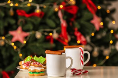 Tarçın ve bulanık Noel ağacı karşı masada kurabiye ile lezzetli sıcak kakao fincan