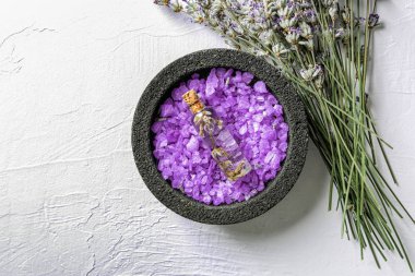 Deniz tuzu ve Lavanta esansiyel yağı ışık arka plan üzerinde şişe ile kase