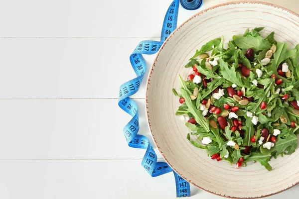 盘子里有美味的健康新鲜沙拉和桌上的卷尺 饮食理念 — 图库照片