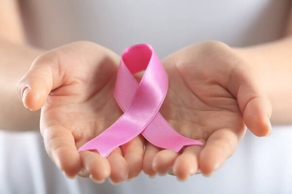 Beautiful woman holding pink ribbon, closeup. Breast cancer concept