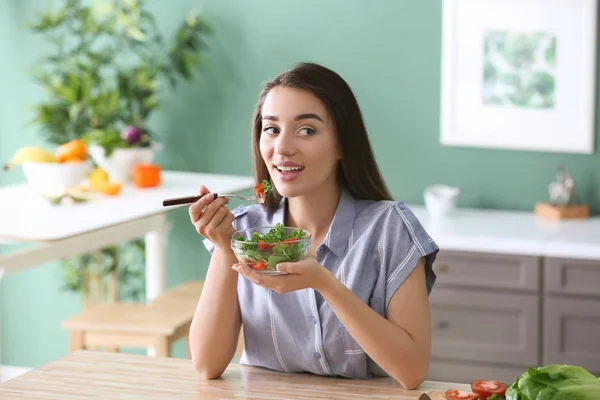 在厨房吃健康沙拉与蔬菜的年轻妇女 — 图库照片