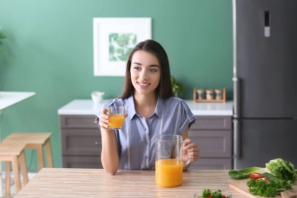 キッチンで新鮮なオレンジ ジュースのガラスを持つ若い女性 — ストック写真