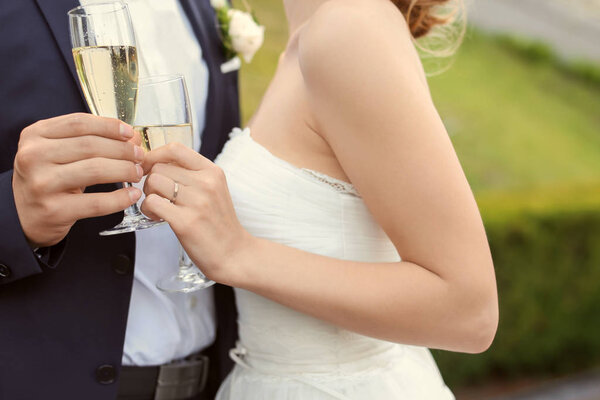 Happy wedding couple with glasses of champagne outdoors