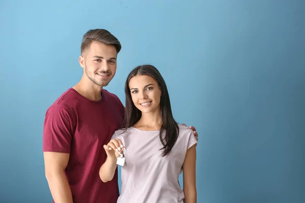 Junges Glückliches Paar Mit Schlüssel Ihres Neuen Hauses Auf Farbigem — Stockfoto