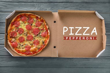 Ahşap masa üzerinde lezzetli biberli pizza ile karton kutu