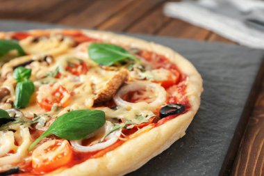 Ahşap masa, closeup üzerinde lezzetli pizza ile kayrak plaka
