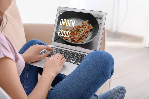 Woman using laptop to order food delivery online at home