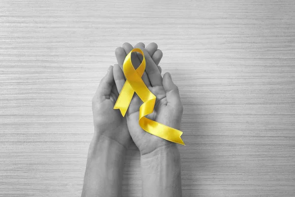 Mãos Femininas Segurando Fita Amarela Fundo Claro Conceito Cancro — Fotografia de Stock
