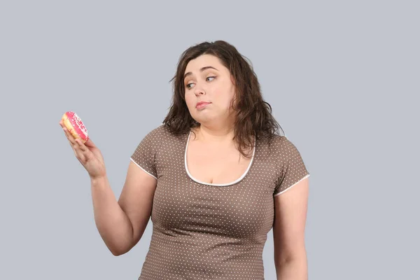 灰色の背景にドーナツと若いたくましい女性 ダイエット食品のコンセプト — ストック写真