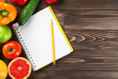 Sebze, meyve ve ahşap arka plan üstünde defter. Diyet gıda