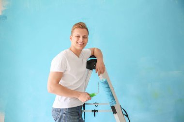 Silindir konumu merdiven renk arka plan üzerinde olan genç erkek ressam