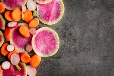 Olgun dilimlenmiş turp ve havuç gri arka planda, üstten görünüm