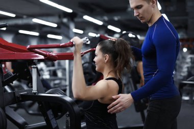 Sportif kadın spor salonunda antrenör onun gözetimi altında egzersizleri yapıyor