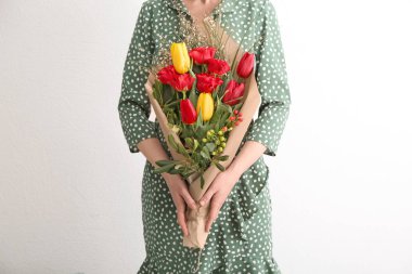 Güzel çiçekler ışık arka plan üzerinde hediye olarak tutan kadın