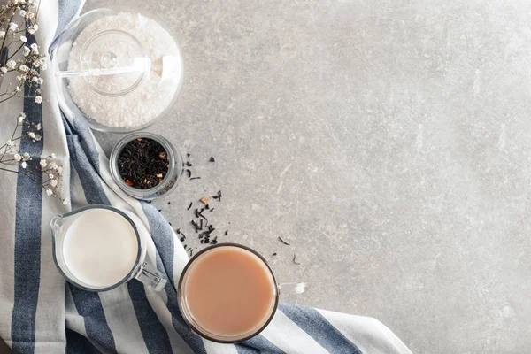 Composition with cup of tea and milk on gray background, top view