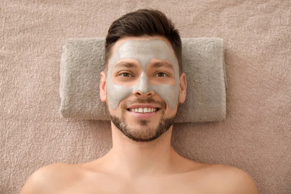 Handsome man with cosmetic mask in spa salon
