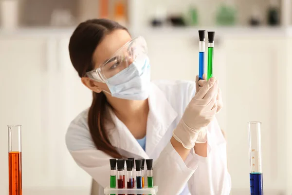 女性の科学者が研究室で試験管の色のサンプルを保持 — ストック写真