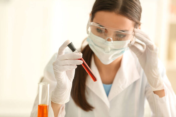 Female scientist holding test tube with color sample in laboratory