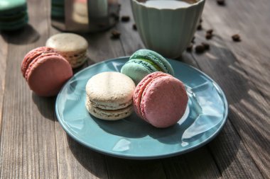Lezzetli macarons ve ahşap zemin üzerine kahve ile plaka