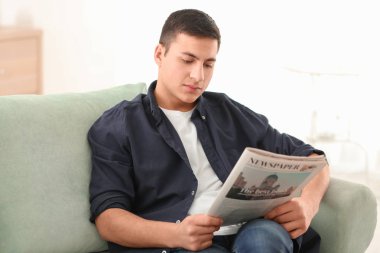 Yakışıklı adam evde kanepe üzerinde gazete okuma