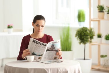 Kafede gazete okuyan genç bir kadın.