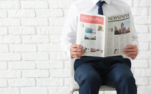 Geschäftsmann Sitzt Auf Stuhl Beim Zeitungslesen Vor Backsteinwand Hintergrund — Stockfoto