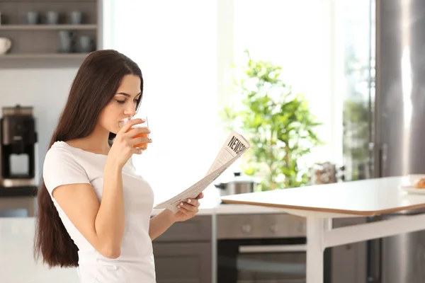 Junge Frau Liest Zeitung Während Sie Der Küche Saft Trinkt — Stockfoto