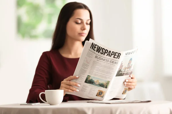 在咖啡馆里看报纸的年轻女人 — 图库照片