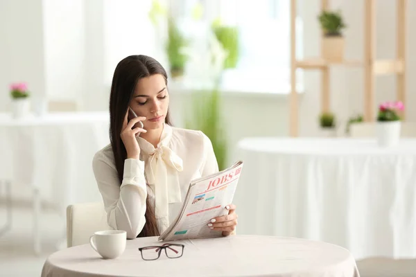 Young Woman Reading Newspaper While Talking Mobile Phone Cafe — Stock Photo, Image