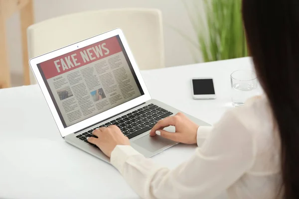 Young woman reading news on laptop screen indoors