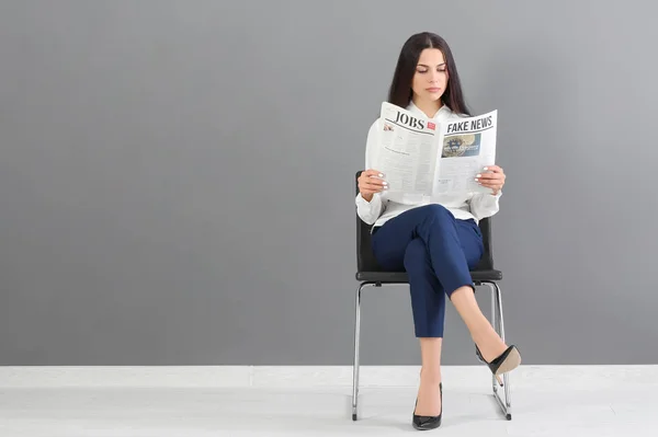 Mujer Joven Leyendo Periódico Contra Pared Gris — Foto de Stock