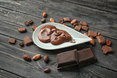 Ahşap masa üzerinde erimiş çikolata ve kakao çekirdekleri ile plaka