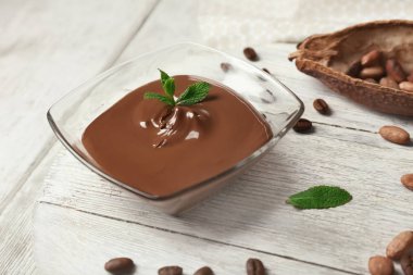 Ahşap masa üzerinde erimiş çikolata ile cam kase