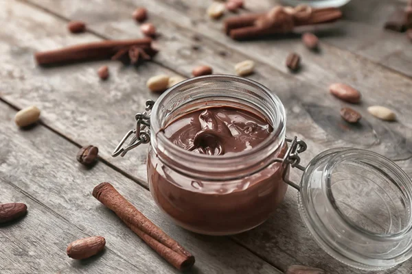 Ahşap masa üzerinde erimiş çikolata ile jar