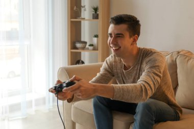 Genç adam evde video oyunu oynuyor.
