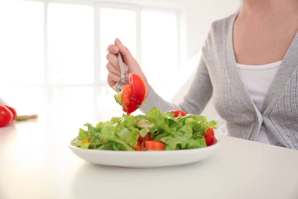 Young woman eating fresh salad at home. Healthy food concept