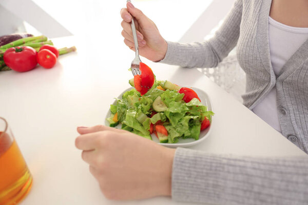 Young woman eating fresh salad at home, closeup. Healthy food concept