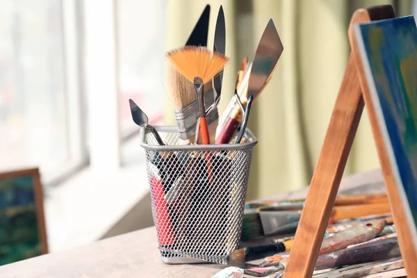 Table with paint tools in artist's workshop