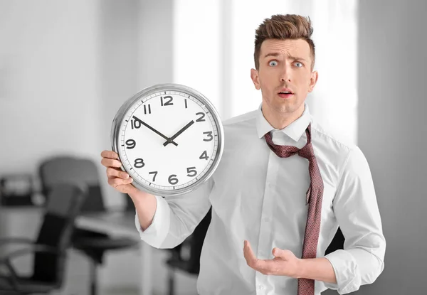 Troubled businessman with clock in office. Time management concept