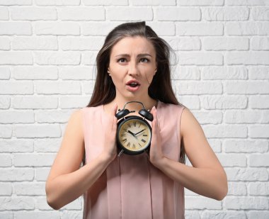 Çalar saat beyaz duvara karşı olan sorunlu kadın. Zaman yönetimi kavramı