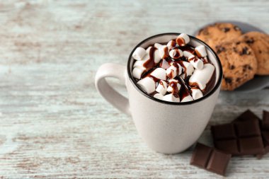 Bir fincan sıcak çikolata ve ahşap masa üzerinde lokum.