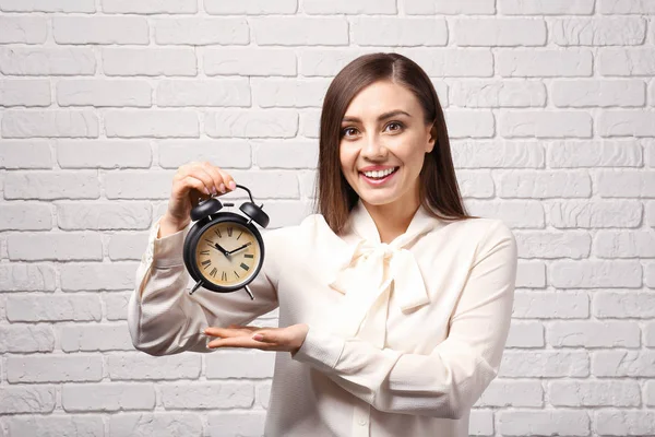 Vrouw Met Wekker Tegen Witte Bakstenen Muur Time Management Concept — Stockfoto