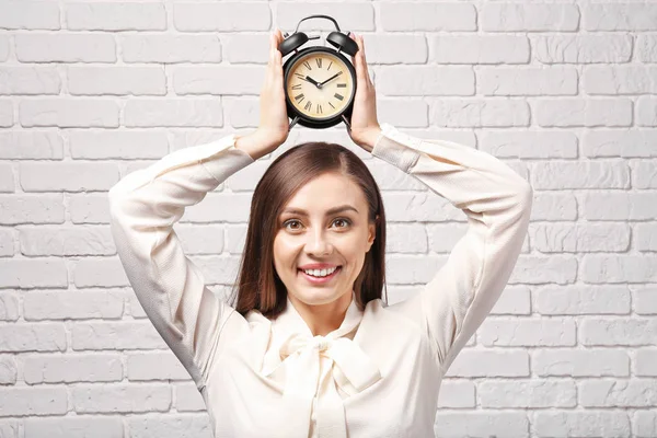 Vrouw Met Wekker Tegen Witte Bakstenen Muur Time Management Concept — Stockfoto