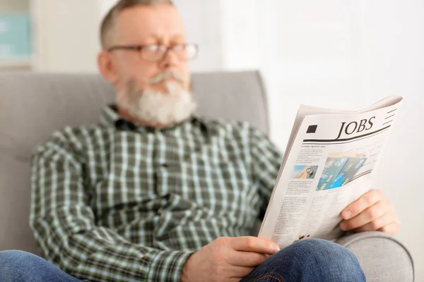 Senior man reading newspaper at home